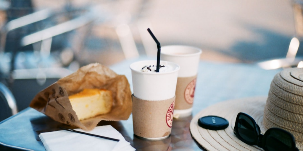 Two cups off coffee and a pastry sitting on a cafe table