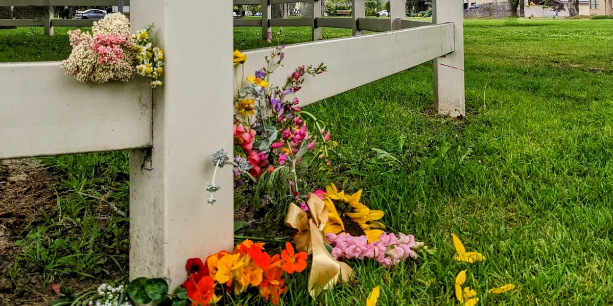 Assorted floral bouquets piled against a fence