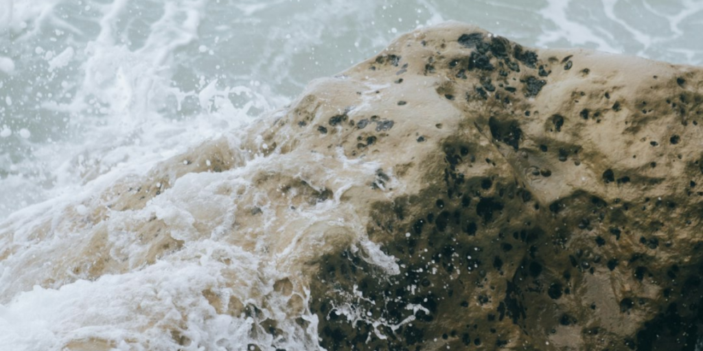 A wave splashing against a large rock