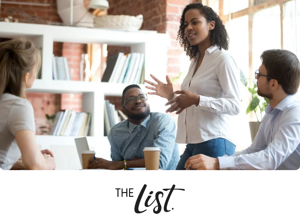 Stock image of a woman standing up to lead a business meeting with 3 other people looking at her speaking.