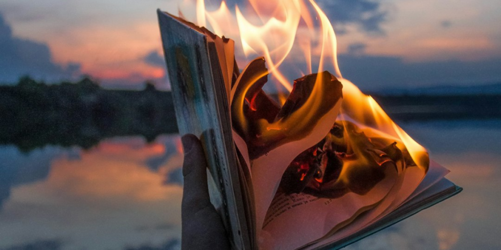 A burning is burning in flamed with the sunset in the background.