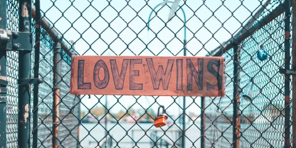 A "love wins" sign hung up on a metal fence.