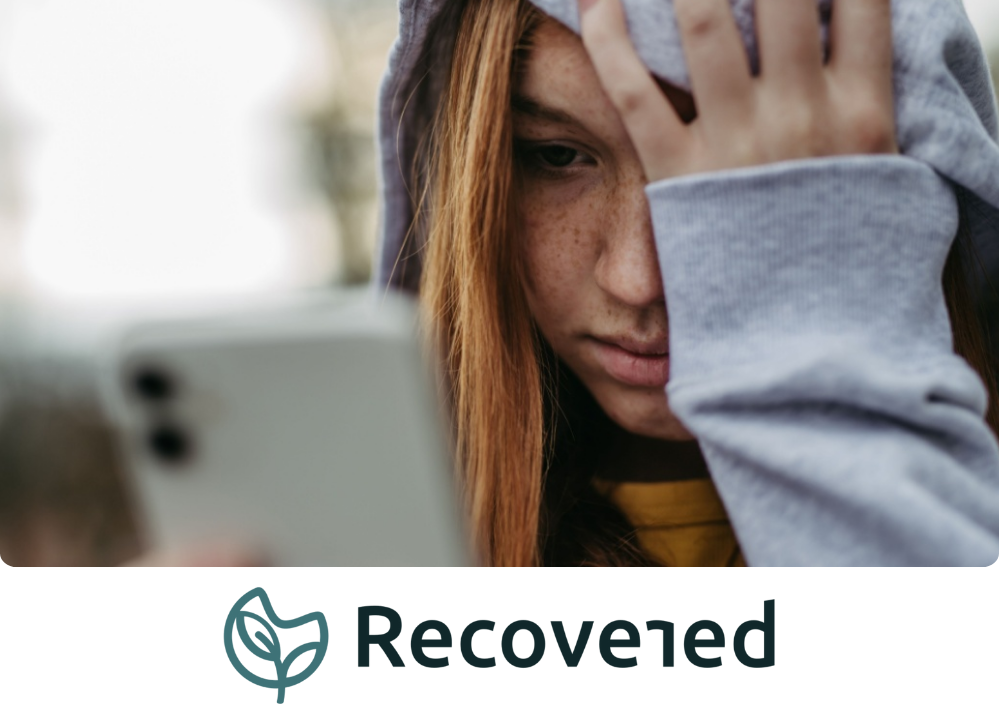 Stock Image of a girl looking at her phone with her hand on her face.