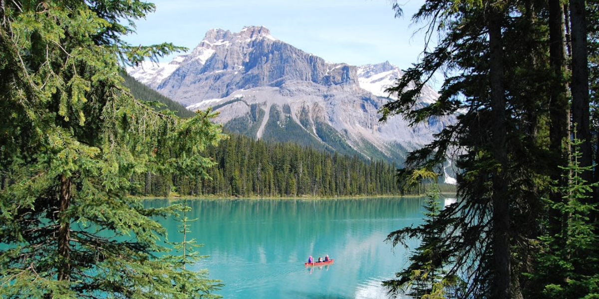 A photo from Banff, Canada with a kayak on a lake surrounded by trees and mountains.