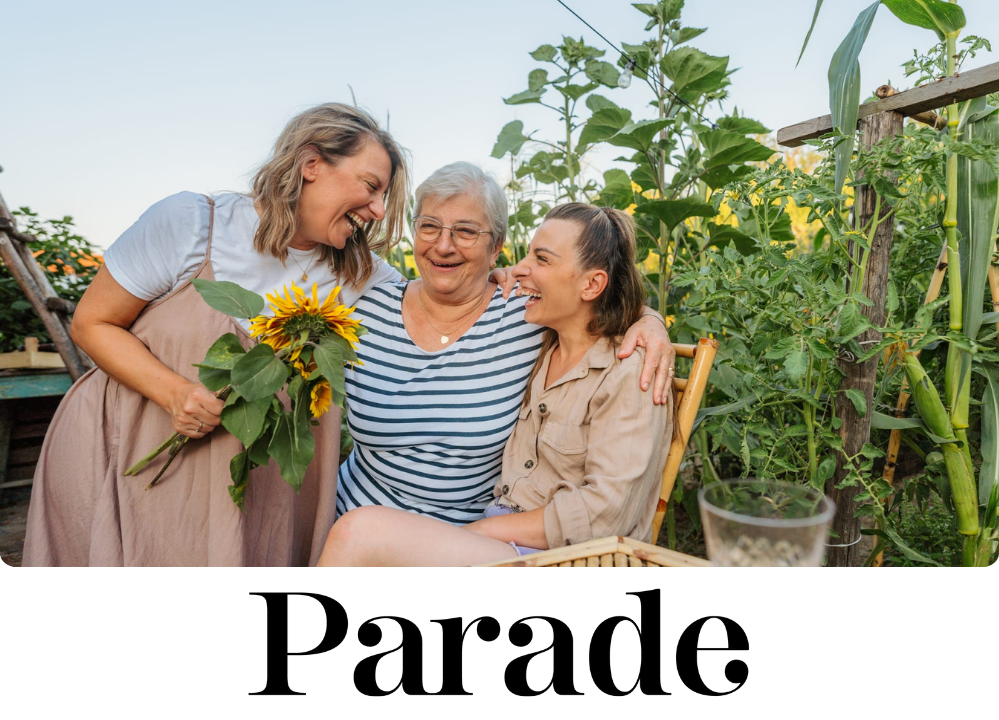 Stock Image of three women, seemingly an older mother and her two daughters, smiling and hugging in a backyard.